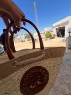 Cabas tressé naturel avec anses et motif circulaire, photographié en extérieur